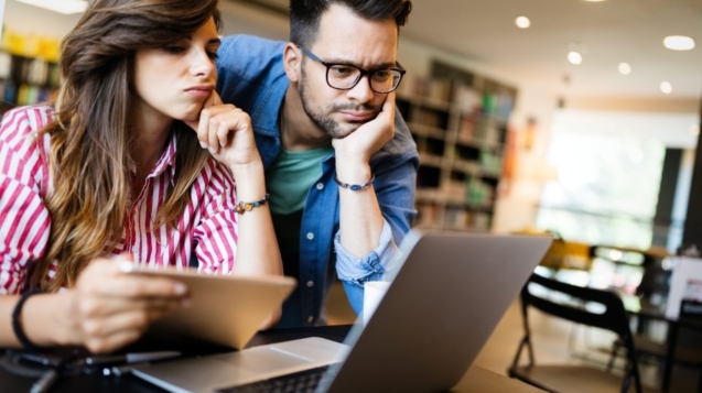 Two colleagues looking thoughtfully at a laptop and tablet