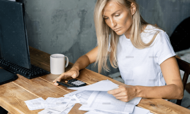 Woman reviewing paperwork with a calculator at her desk