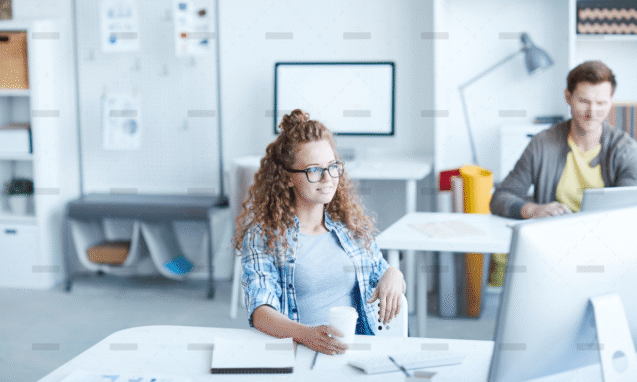 Woman with glasses smiling at her desk in a bright office